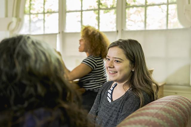 Photo of a student taking notes on a laptop with Chatham University sticker during a lecture. 