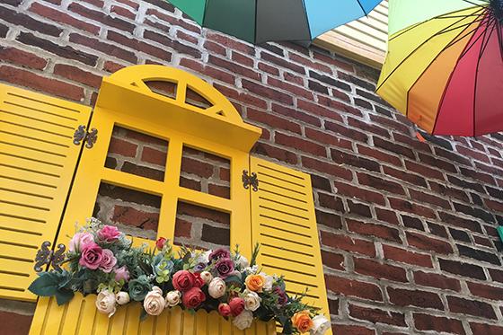 Photo of a cafe in Pittsburgh with rainbow umbrellas and a bright yellow window